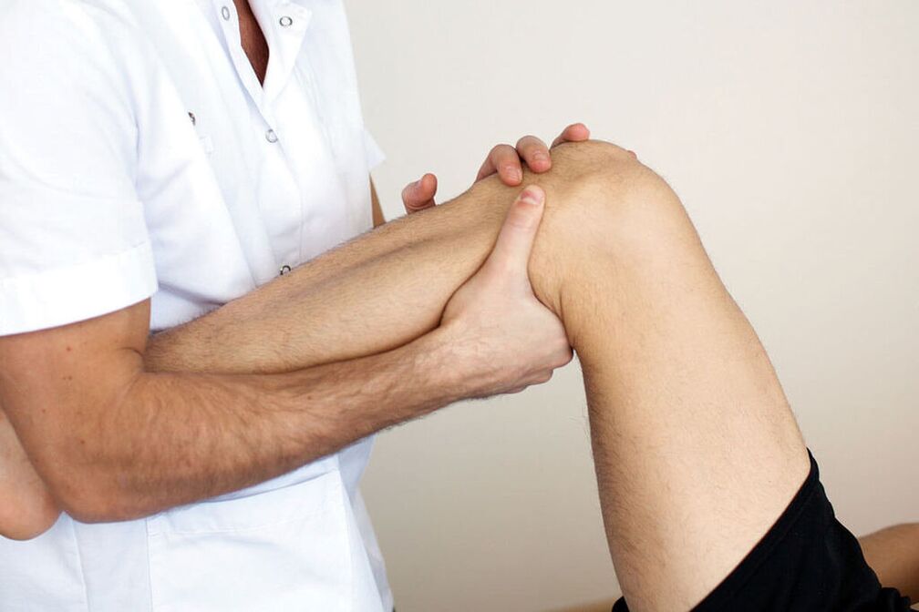 Il medico esamina un ginocchio con osteoartrite